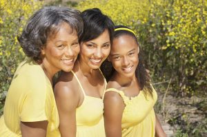 Grandmother, mother and daughter smiling near flowers